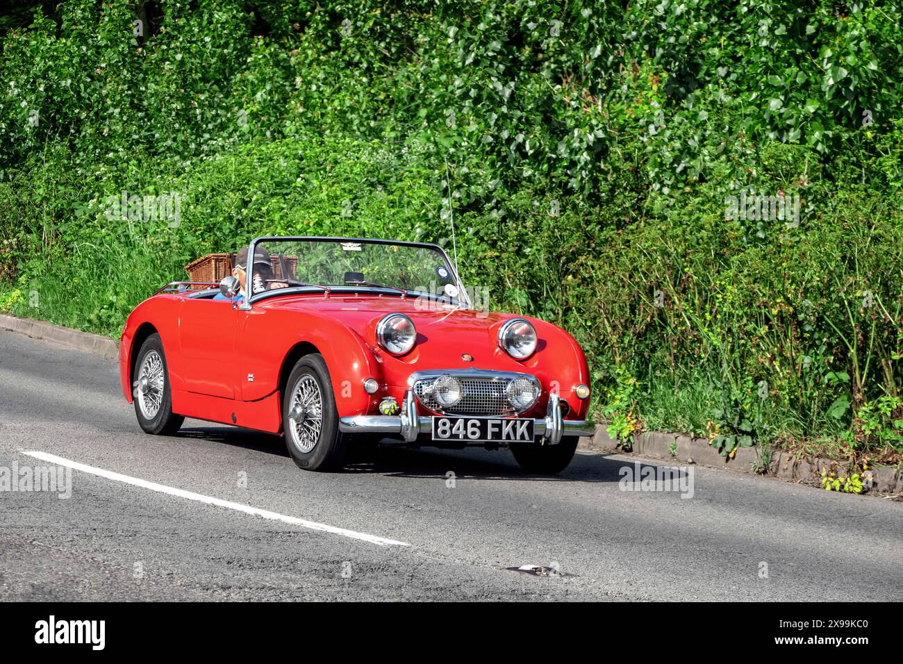 Austin Healey Sprite MkI che guida lungo una strada di campagna inglese Foto Stock