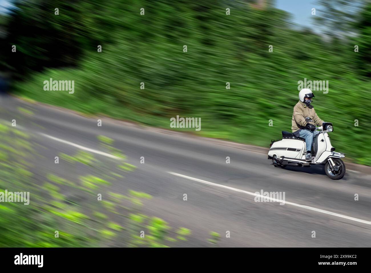 Scooter Lambretta degli anni '1960 che viaggia lungo una strada di campagna inglese Foto Stock