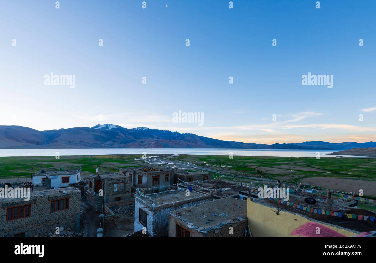 Terreni agricoli e borghi con bandiere di preghiera appese sui tetti, accanto al TSO Moriri (lago Moriri) ad alta quota nell'altopiano di Changthang, Ladakh, India Foto Stock