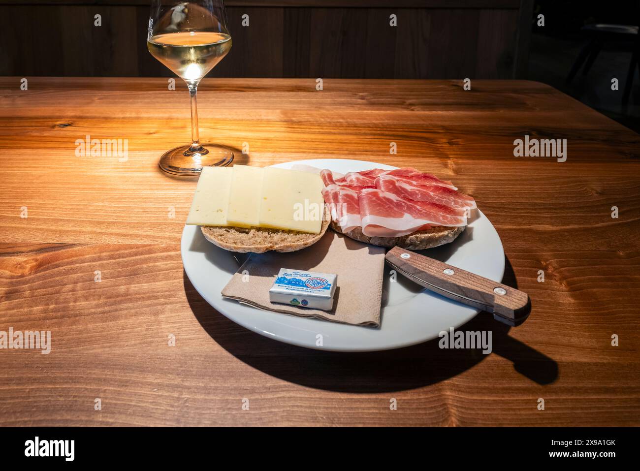 Bicchiere di vino bianco e pane con formaggio locale e prosciutto affumicato speck, alto Adige, Italia Foto Stock
