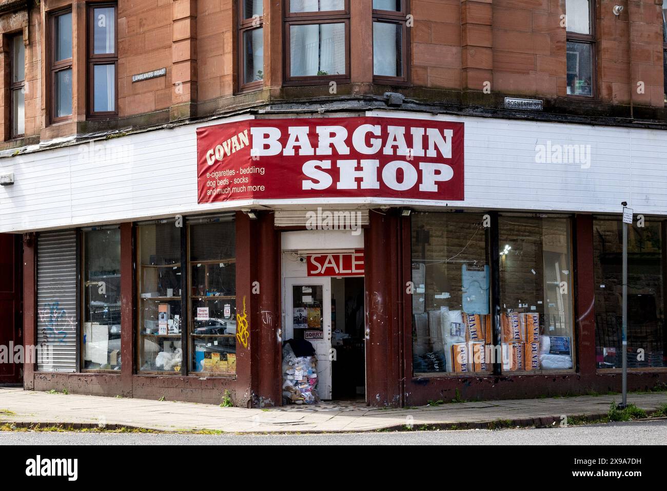 Govan Red arenaria Tenement Buildings and Bargain Shop, Govan, Glasgow, Scozia, Regno Unito Foto Stock