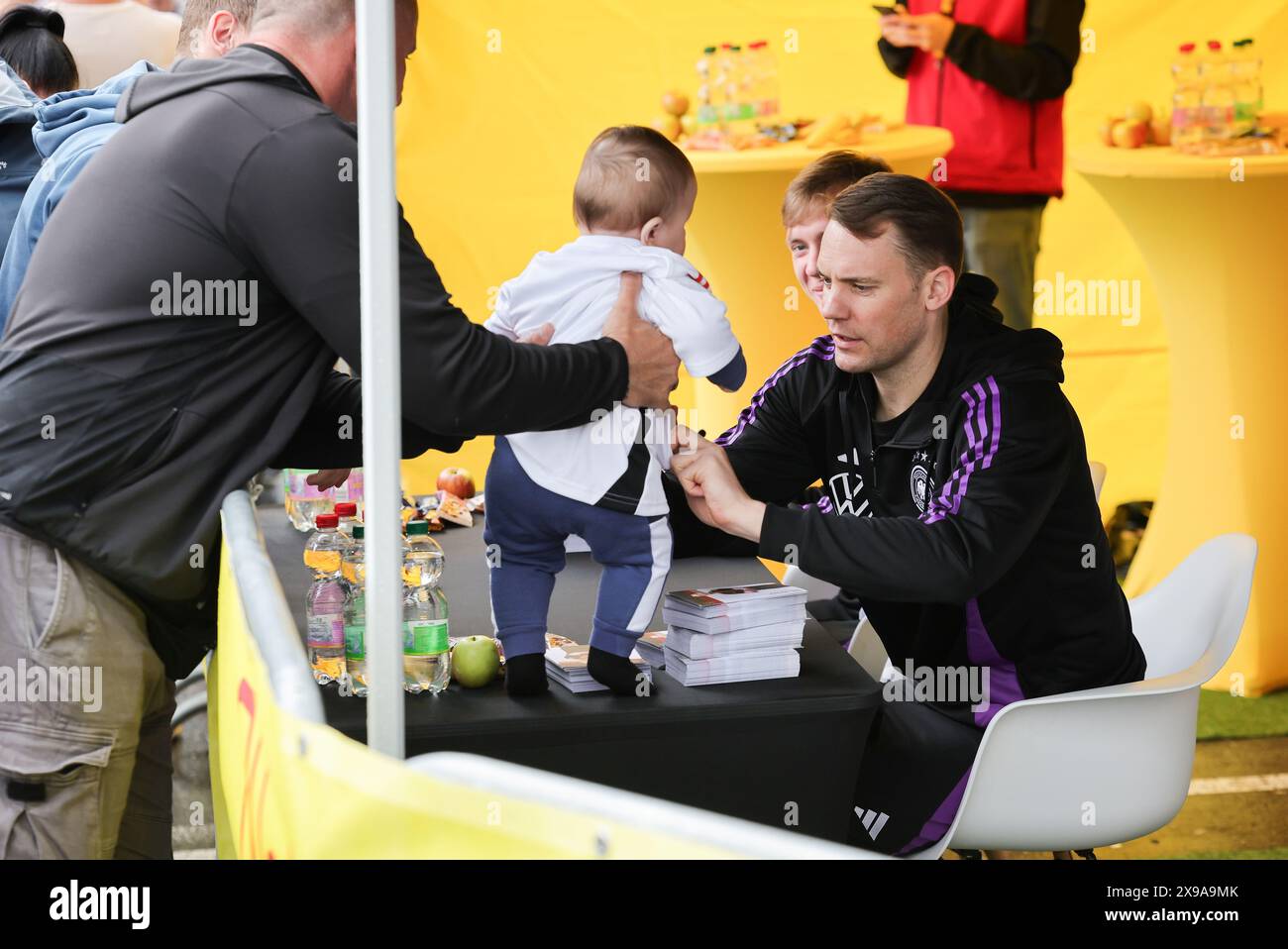 30 maggio 2024, Turingia, Blankenhain: Calcio: Squadra nazionale, preparazione al campionato europeo di casa, campagna tifosi a Blankenhain. Il portiere Manuel Neuer (r) e Maximilian Beier firmano autografi durante una campagna di tifosi in un supermercato. Neuer firma una maglia da bambino qui. Foto: Christian Charisius/dpa - NOTA IMPORTANTE: In conformità con le normative della DFL German Football League e della DFB German Football Association, è vietato utilizzare o far utilizzare fotografie scattate nello stadio e/o della partita sotto forma di immagini sequenziali e/o serie di foto video. Foto Stock