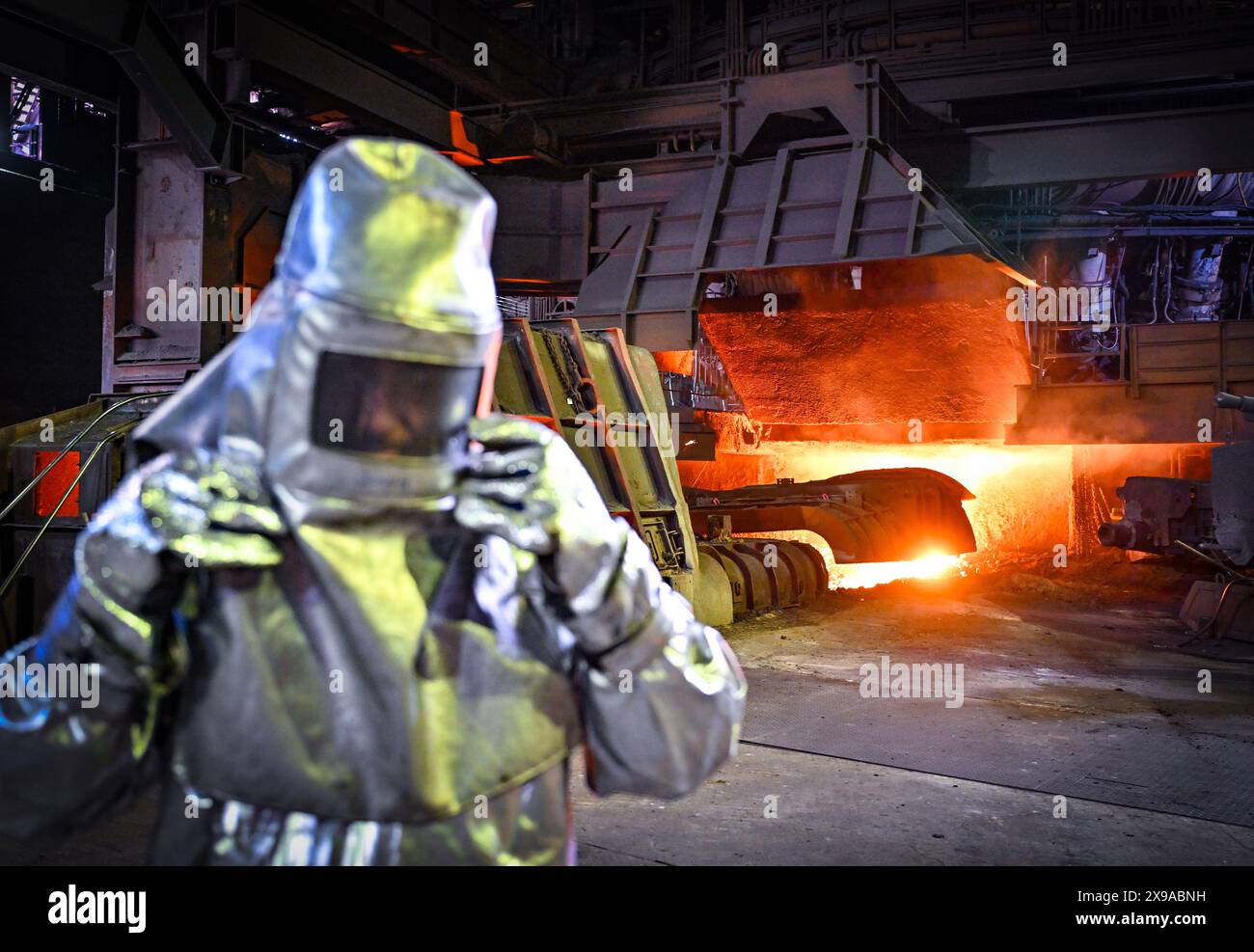 30 maggio 2024, Brandeburgo, Eisenhüttenstadt: Un dipendente di abbigliamento protettivo sta toccando la ghisa in un altoforno presso la ArcelorMittal Eisenhüttenstadt GmbH. Nel pomeriggio, il ministro dell'economia federale Habeck (Verdi) dovrebbe consegnare ad ArcelorMittal una sovvenzione per la produzione di acciaio climaticamente neutrale. Il progetto congiunto di decarbonizzazione dei siti di Eisenhüttenstadt e Brema è di notevole importanza per il futuro dei due stabilimenti di acciaio piano di ArcelorMittal in Germania. Foto: Patrick Pleul/dpa Foto Stock