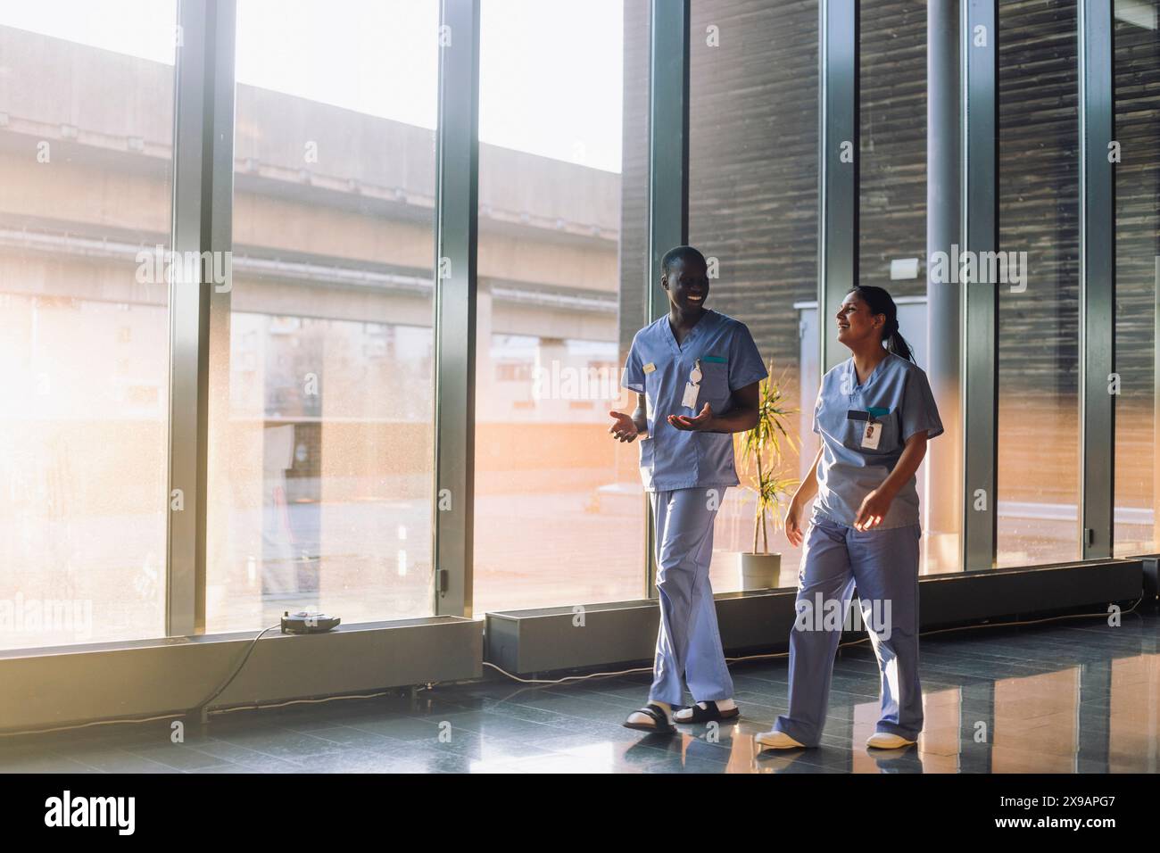 Full length shot di professionisti medici felici discutere mentre cammina in ospedale Foto Stock