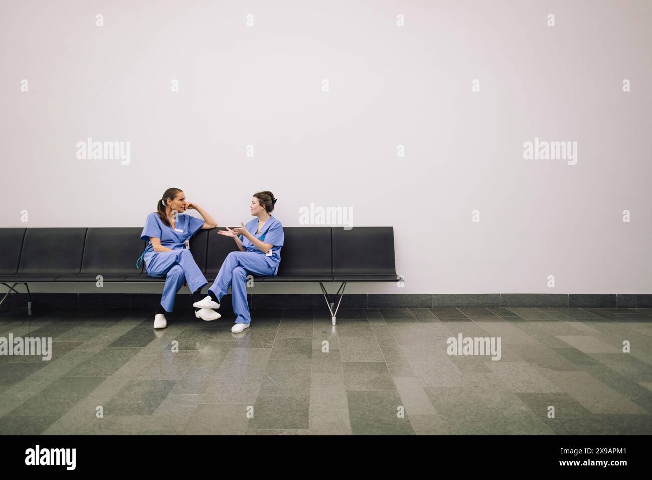 Donne dottori che discutono mentre sono sedute in panchina in ospedale Foto Stock