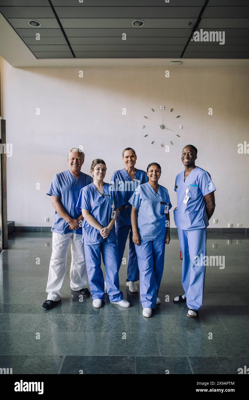 Ritratto di un team sanitario diverso sorridente in scrub blu in piedi insieme in ospedale Foto Stock