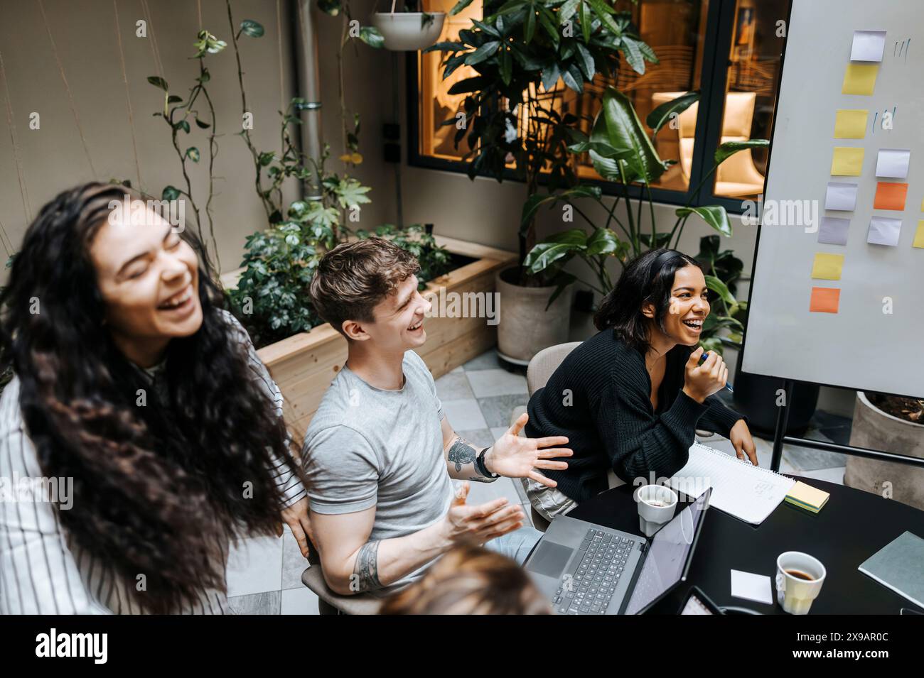 Vista ad alto angolo di imprenditori felici e felici che discutono durante la riunione del team in ufficio Foto Stock