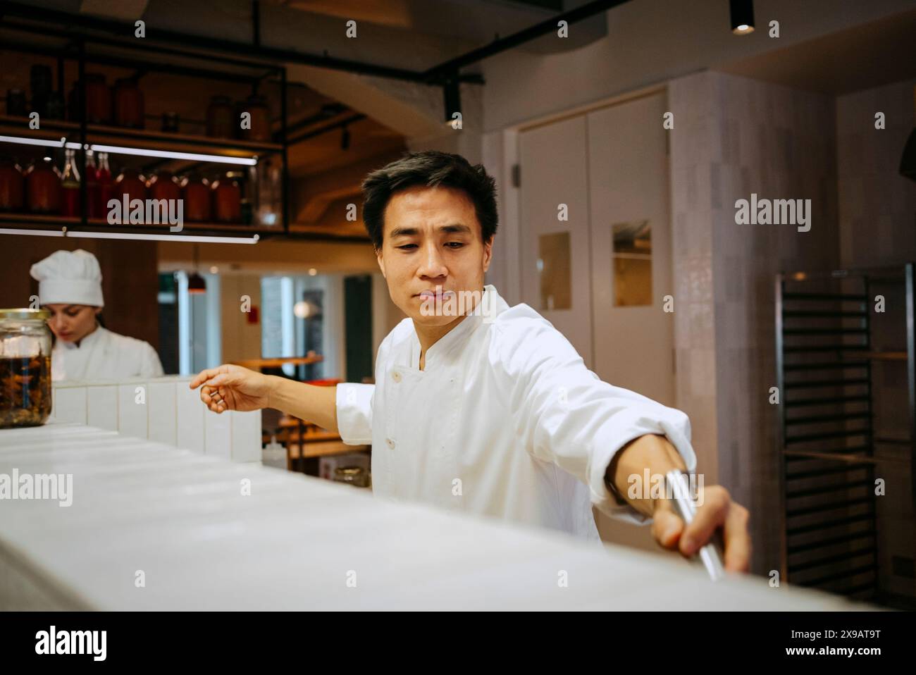 Chef maschile che lavora con colleghi in cucina commerciale Foto Stock