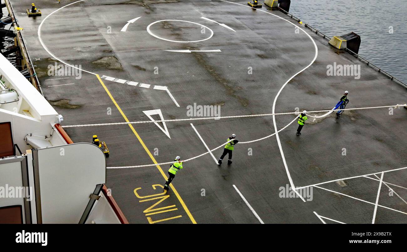 La nuova nave da crociera di Cunard “Queen Anne” arriva a Kirkwall martedì 28 maggio 2024. I lavoratori del porto stanno trasportando le grandi funi di ormeggio. Foto Stock