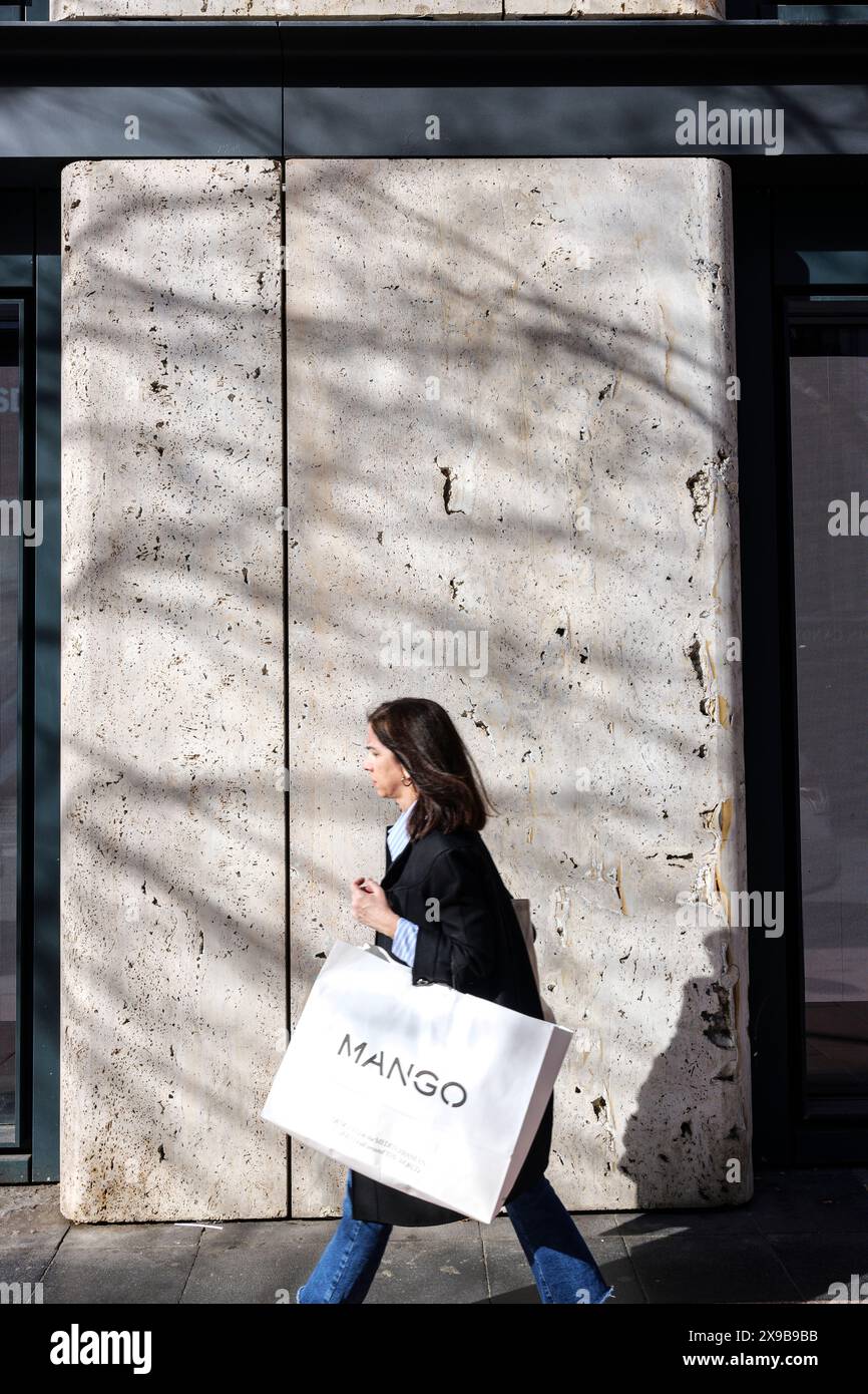 Una donna che cammina all'aperto e porta con sé una borsa da negozio di lusso. Foto Stock