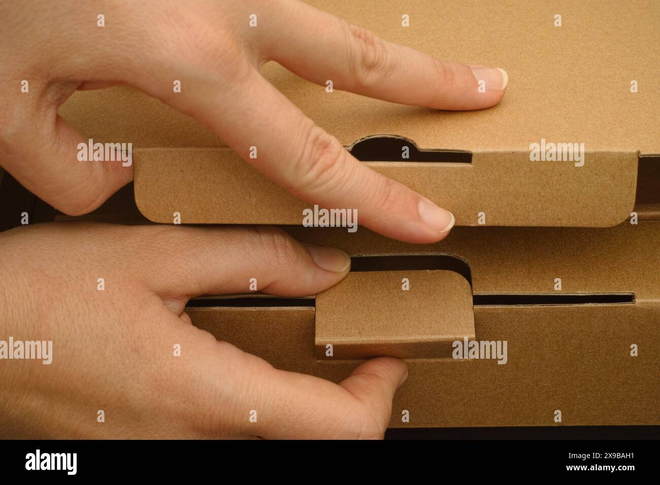 Un primo piano di una donna che apre una scatola di cartone. Foto Stock