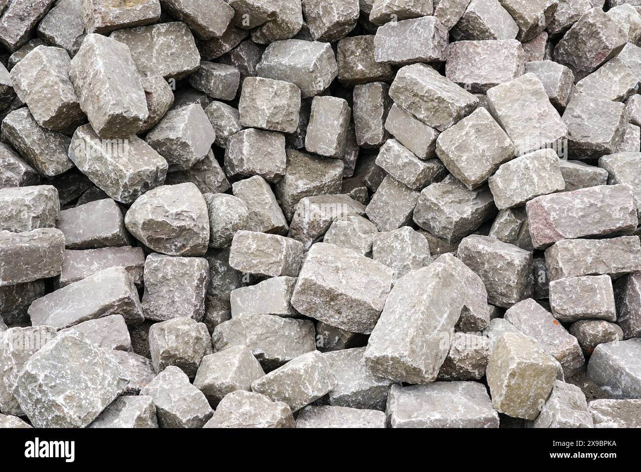 Pile di storici cubi martellati a forma di ciottoli di granito naturale, sfondo di rocce di granito martellate, pietre di granito, pietre di pavimentazione Foto Stock