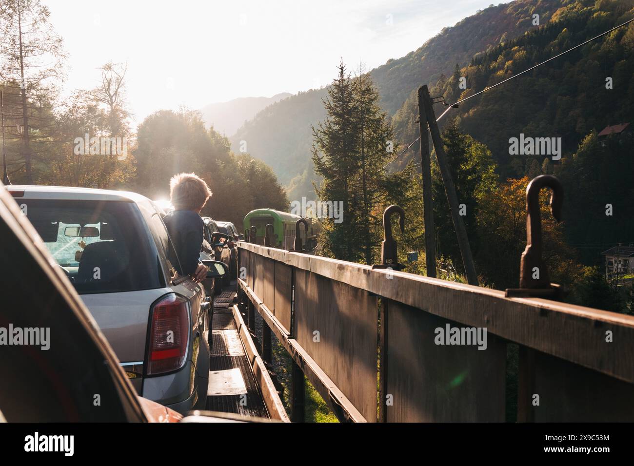 Un ragazzo si appoggia dal finestrino di un'auto su un treno di trasporto di autocarri in Slovenia Foto Stock