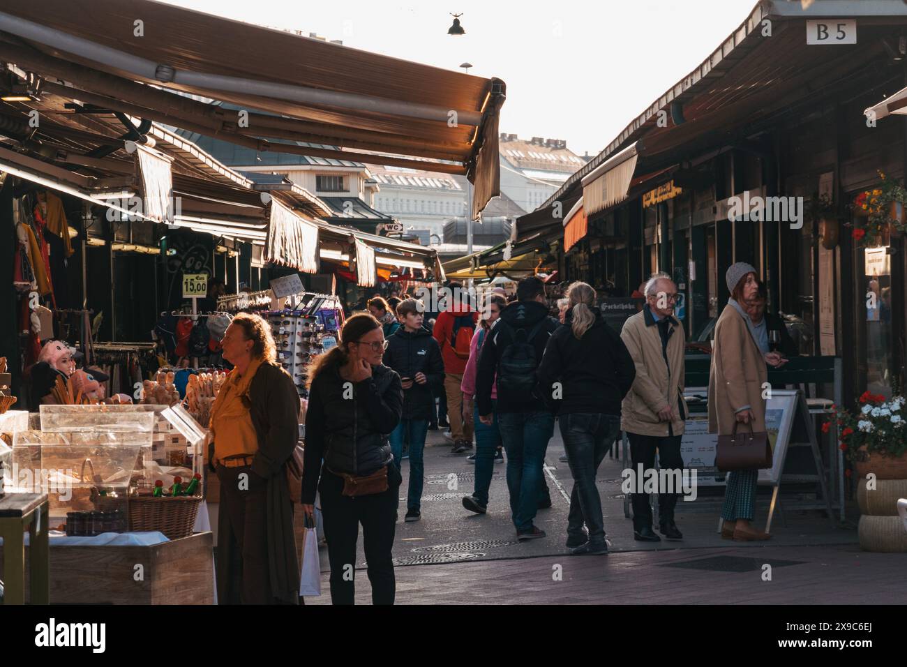 Gli amanti dello shopping curiosano tra i vari stand di Naschmarkt, un mercato all'aperto a Vienna, in Austria, in un soleggiato pomeriggio autunnale Foto Stock