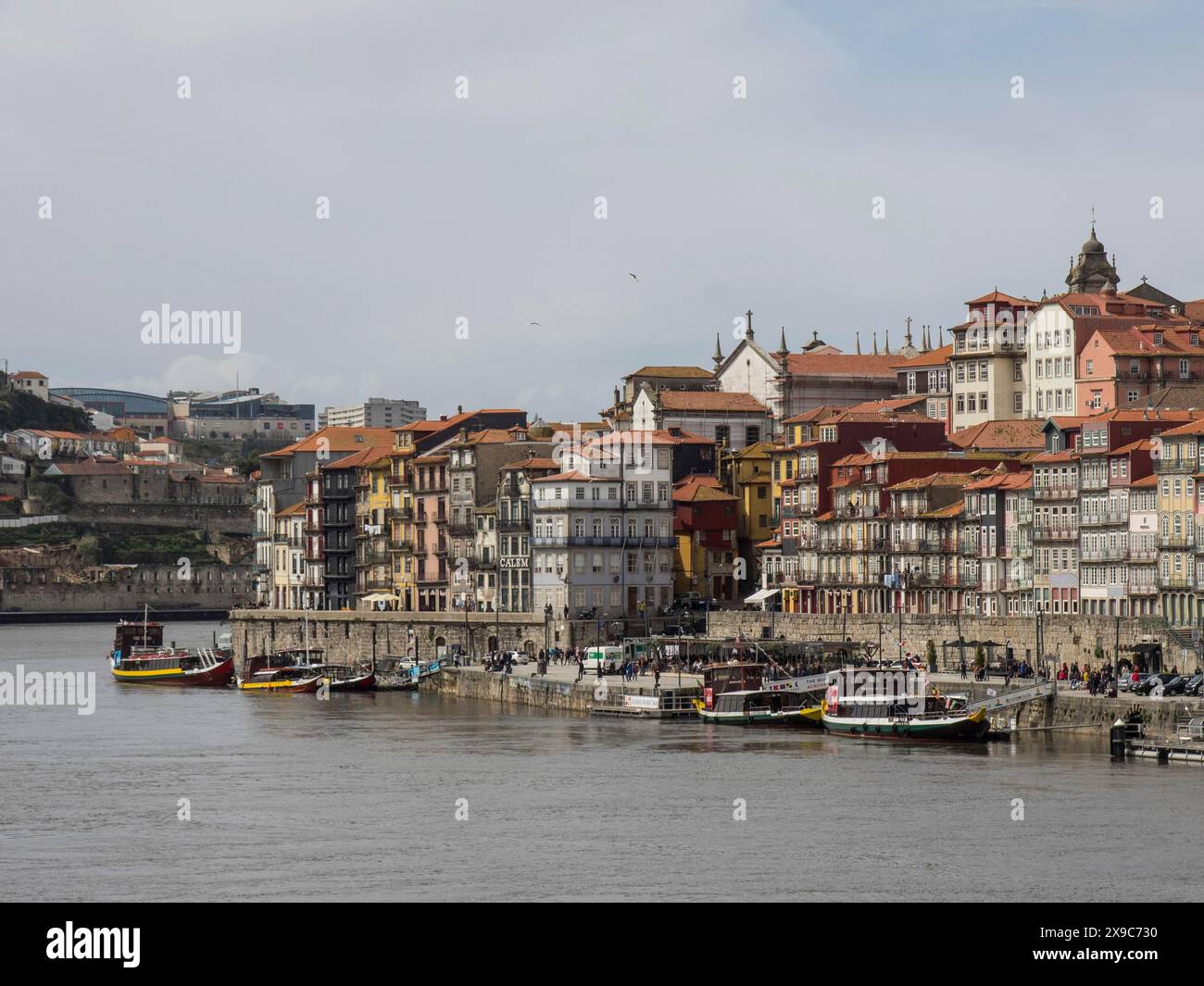 Case storiche sul lungofiume di una città sotto un cielo nuvoloso con diverse barche in acqua, il panorama atlstadt di Porto con case impacchettate su Foto Stock