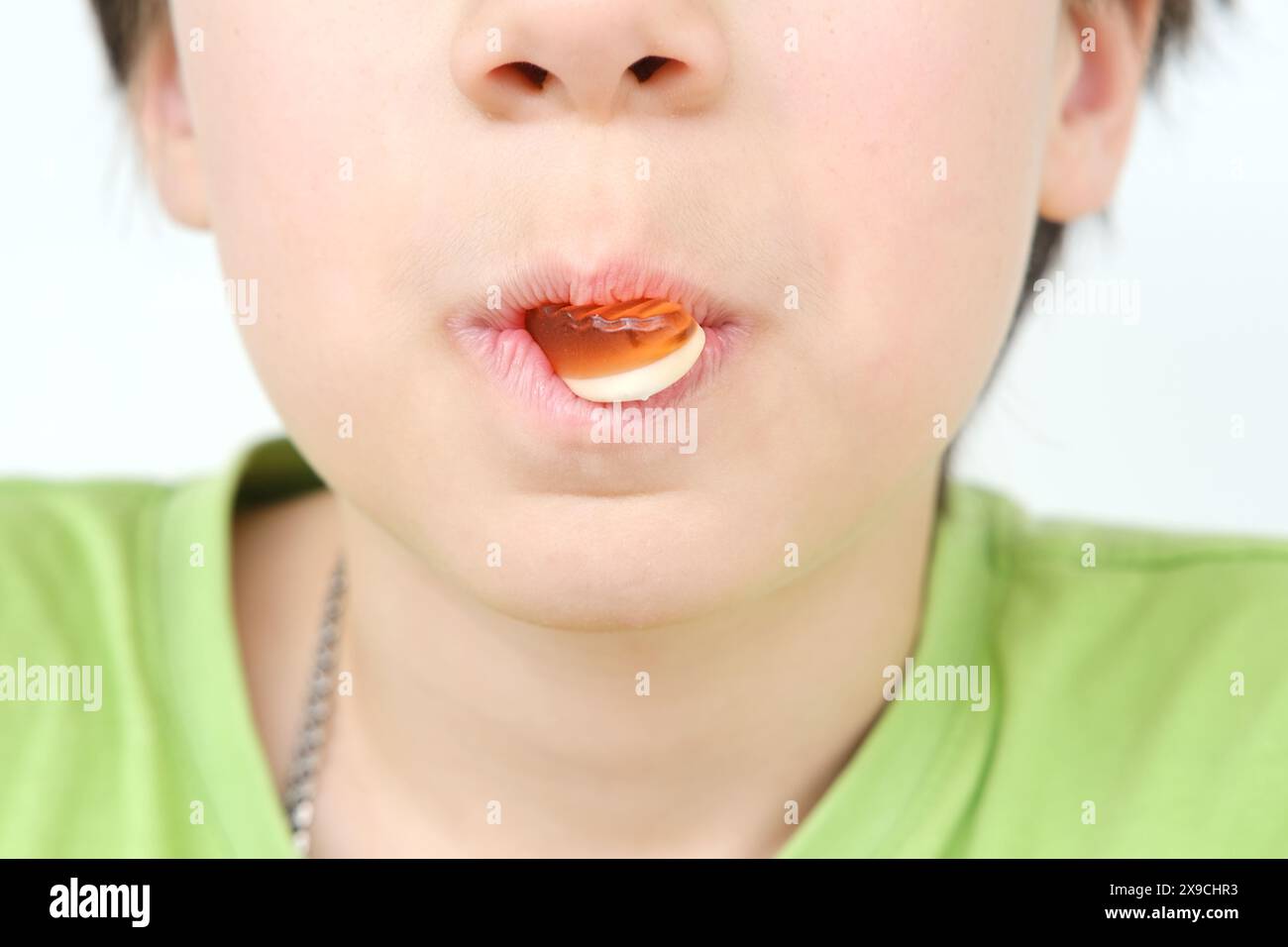 ragazzo, bambino tiene in bocca e mangia dolci gelatinosi, dolci gommosi, concetto di delicatezza per bambini, cibo sano e malsano, cibo halal Foto Stock