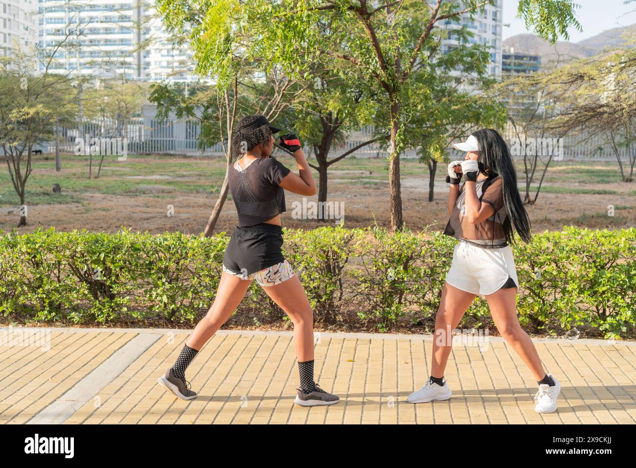 Due donne che praticano tecniche di sparring in una sessione di combattimento fitness all'aperto. Foto Stock