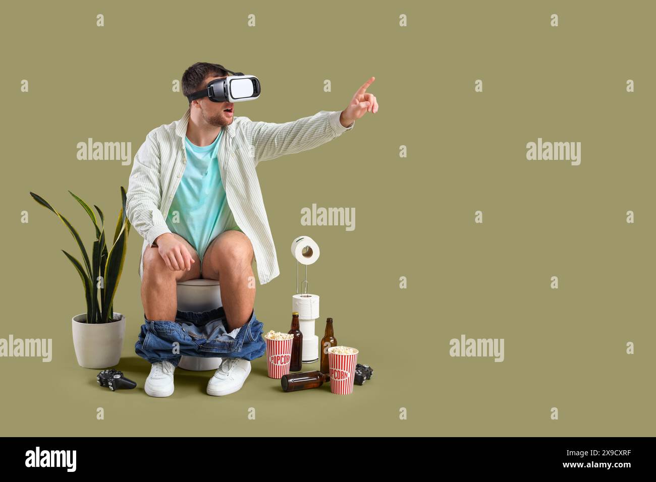 Giovane uomo che usa occhiali VR sulla ciotola del water su sfondo verde Foto Stock