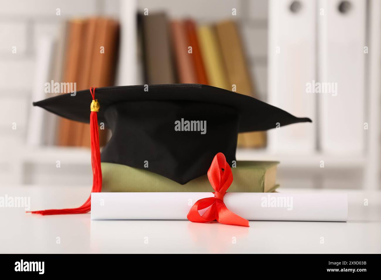 Diploma con libro e mortaio sul tavolo bianco Foto Stock