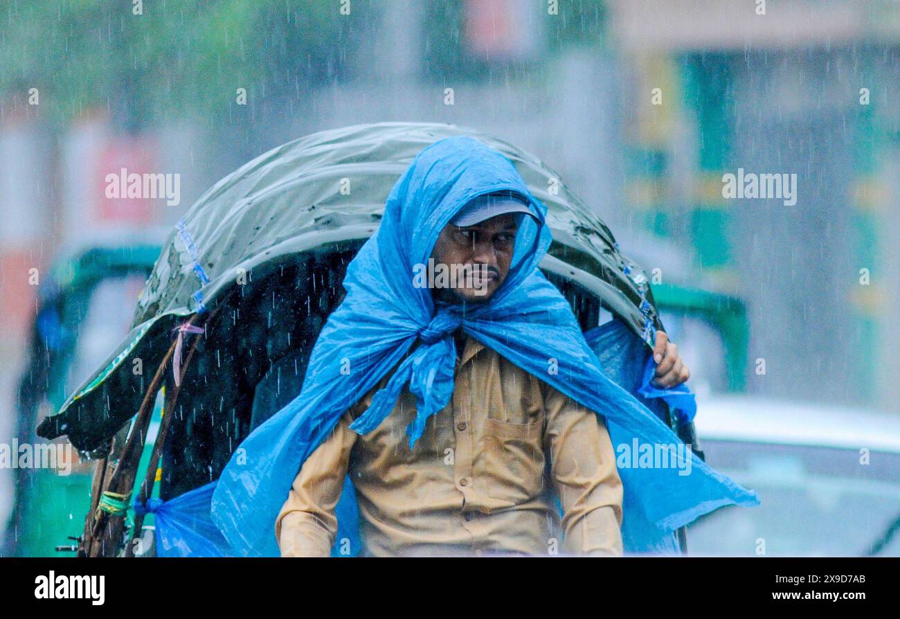 Pedoni che navigano attraverso le strade allagate di Sylhet a causa del ciclone Remal. Negli ultimi giorni, in tutto il paese, sono prevalse forti piogge e le zone costiere hanno subito ingenti danni. Sylhet, Bangladesh. Foto Stock