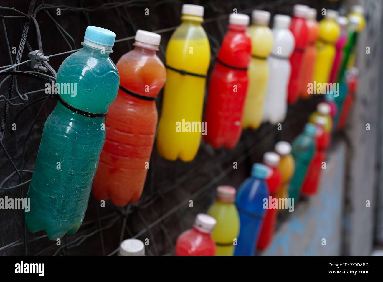 Collezione di bottiglie di plastica colorate appese a una parete Foto Stock