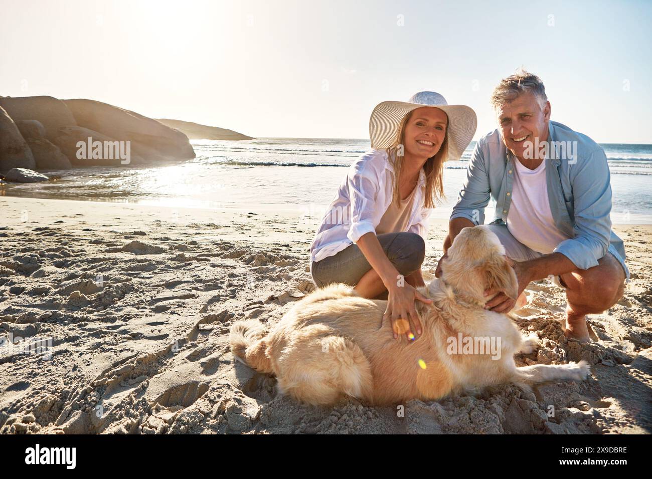 Maturo, ritratto e coppia con il cane in spiaggia per viaggi all'aperto, avventure e vacanze insieme. Uomo, donna e felice sulla sabbia con un animale domestico peloso Foto Stock