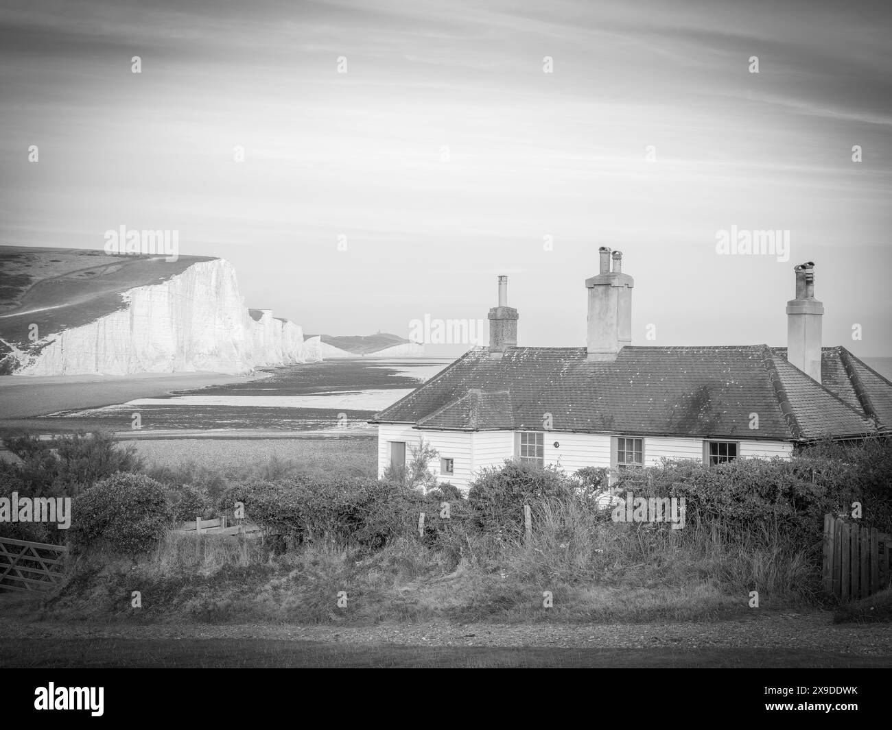 Vista in bianco e nero delle sette Sorelle con un cottage bianco sul davanti. Fotografia di paesaggi e viaggi nostalgici Foto Stock