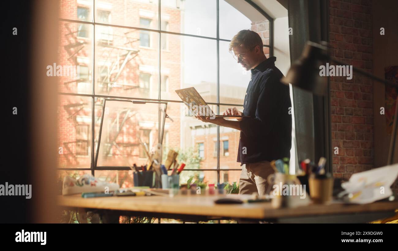 Il designer professionista tiene in mano un laptop, cammina nella sua stanza, scrive codice e controlla i progressi. Bell'uomo che lavora su un'app mobile. Elegante concetto di Studio of Creative Man. Foto Stock