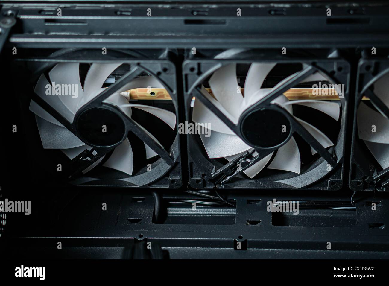 Primo piano delle ventole di raffreddamento del computer all'interno di un case del PC, con tre ventole con lame bianche e cornici nere. Foto Stock