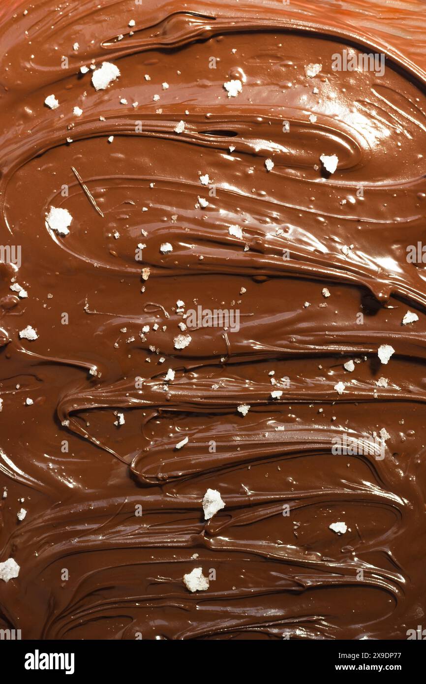 Cioccolato fuso, con scaglie di sale. Sfondo di cioccolato. Foto Stock