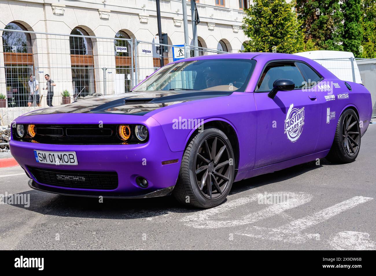 Sibiu, Romania, 15 luglio 2021: Un'auto da corsa americana Dodge viola vivace nel traffico in una strada ad un evento Custom Cars GT in una soleggiata giornata estiva Foto Stock