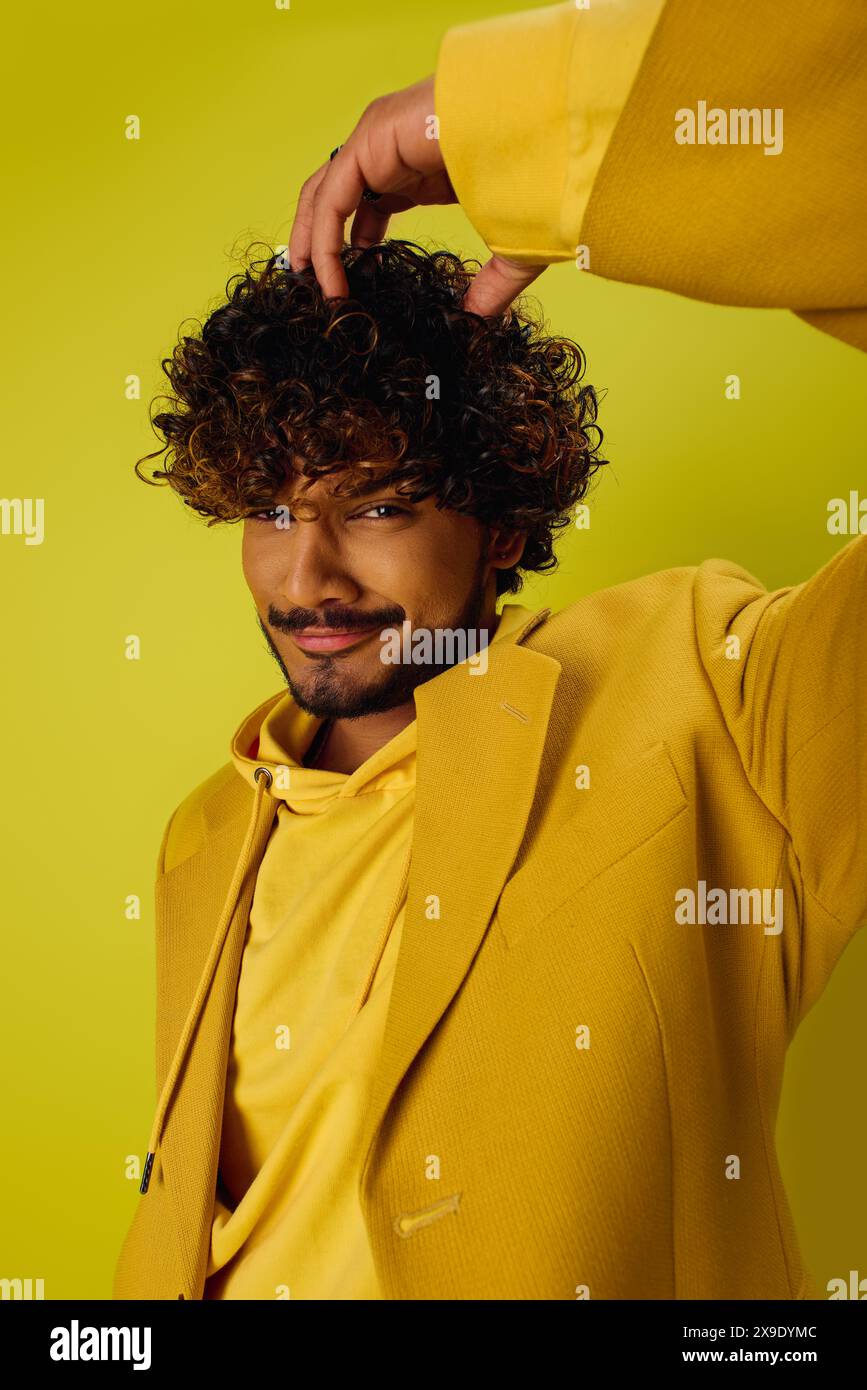 Bell'uomo con capelli ricci in un vestito giallo brillante che posa con sicurezza. Foto Stock