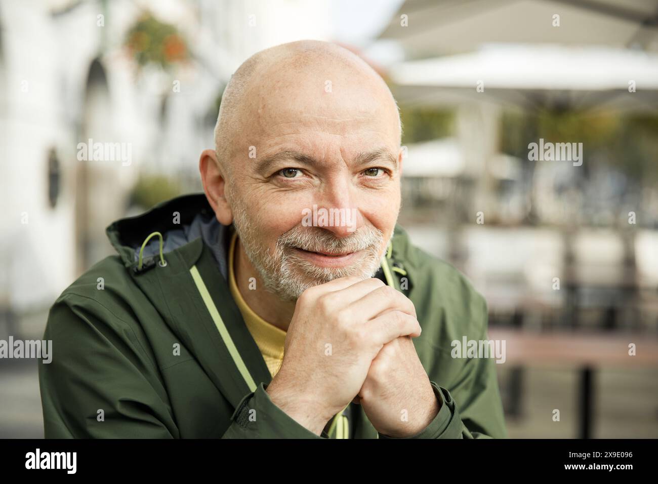 Uomo anziano con barba che riposa Chin a portata di mano in un ambiente urbano all'aperto Foto Stock