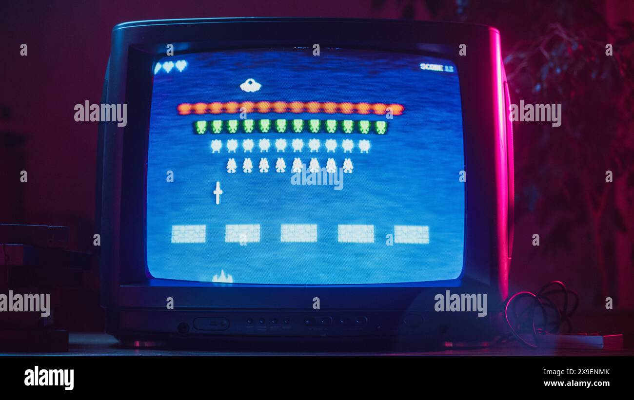 Primo piano di un set TV retrò con un videogioco per console Arcade a 8 bit 2D ispirato agli anni '80. Nostalgic Shooter Game, giocatore Battle con sciame di alieni e vince. Foto Stock