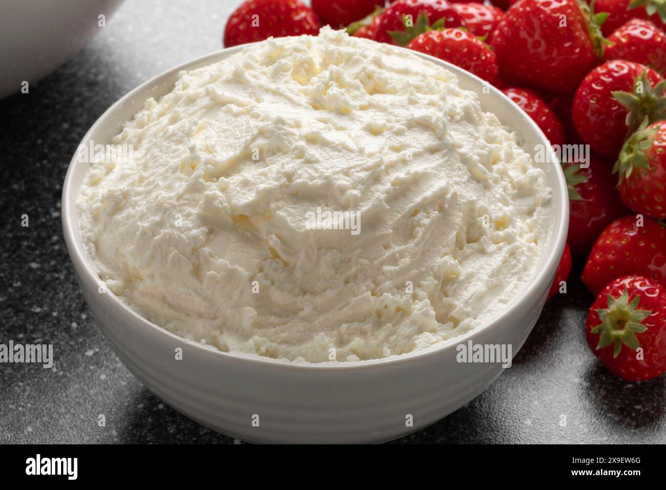 Ciotola bianca con primo piano di Mascarpone italiano e fragole fresche sullo sfondo Foto Stock