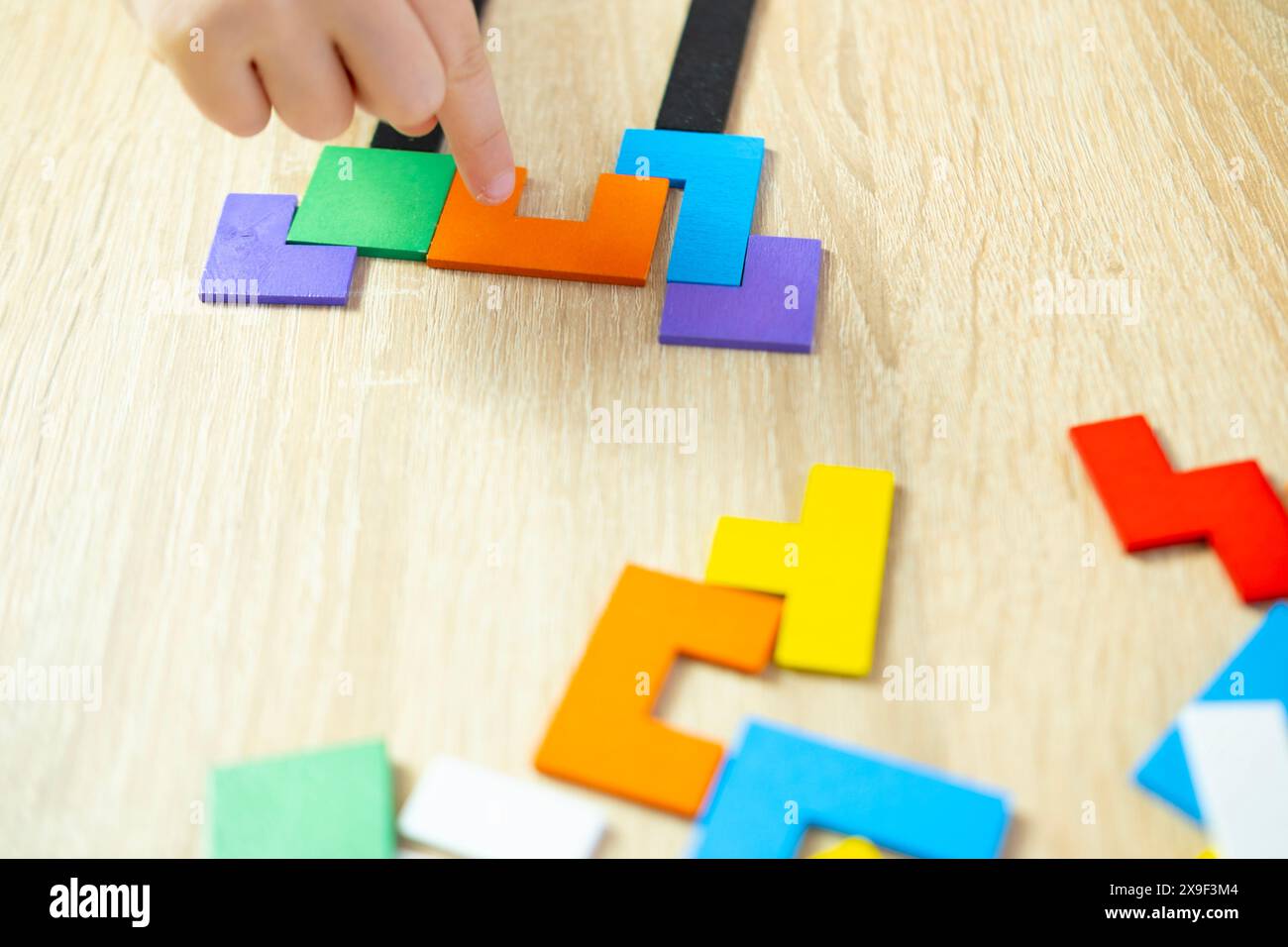 Le mani del bambino manipolano pezzi geometrici di legno colorati puzzle intellettuale, un bambino intelligente risolve il problema, lo sviluppo del cervello, le abilità motorie Foto Stock