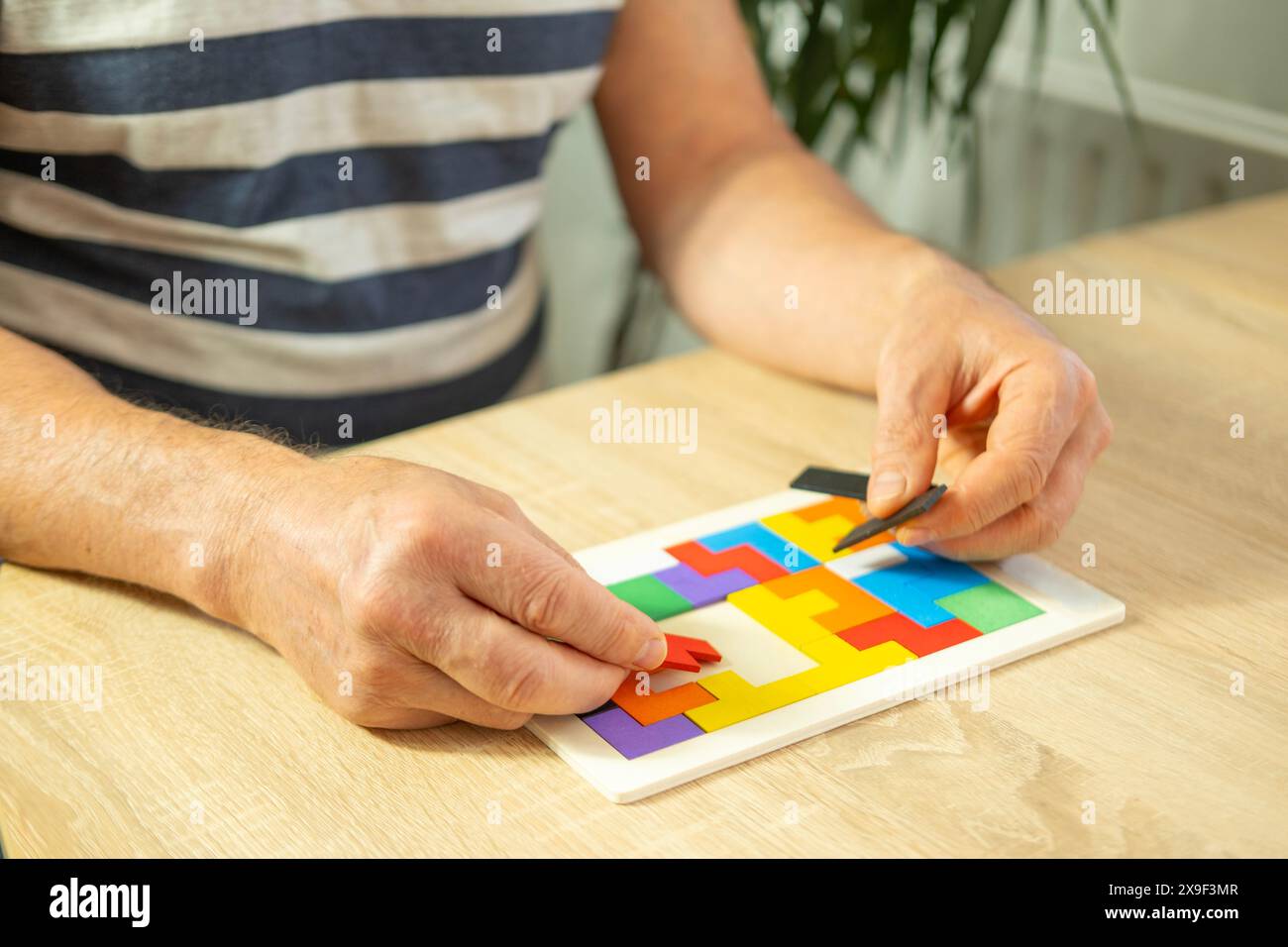 mano maschile manipola puzzle di legno colorato, vecchio anziano che compone forme geometriche, salute del cervello e benessere mentale, prevenire la demenza e. Foto Stock