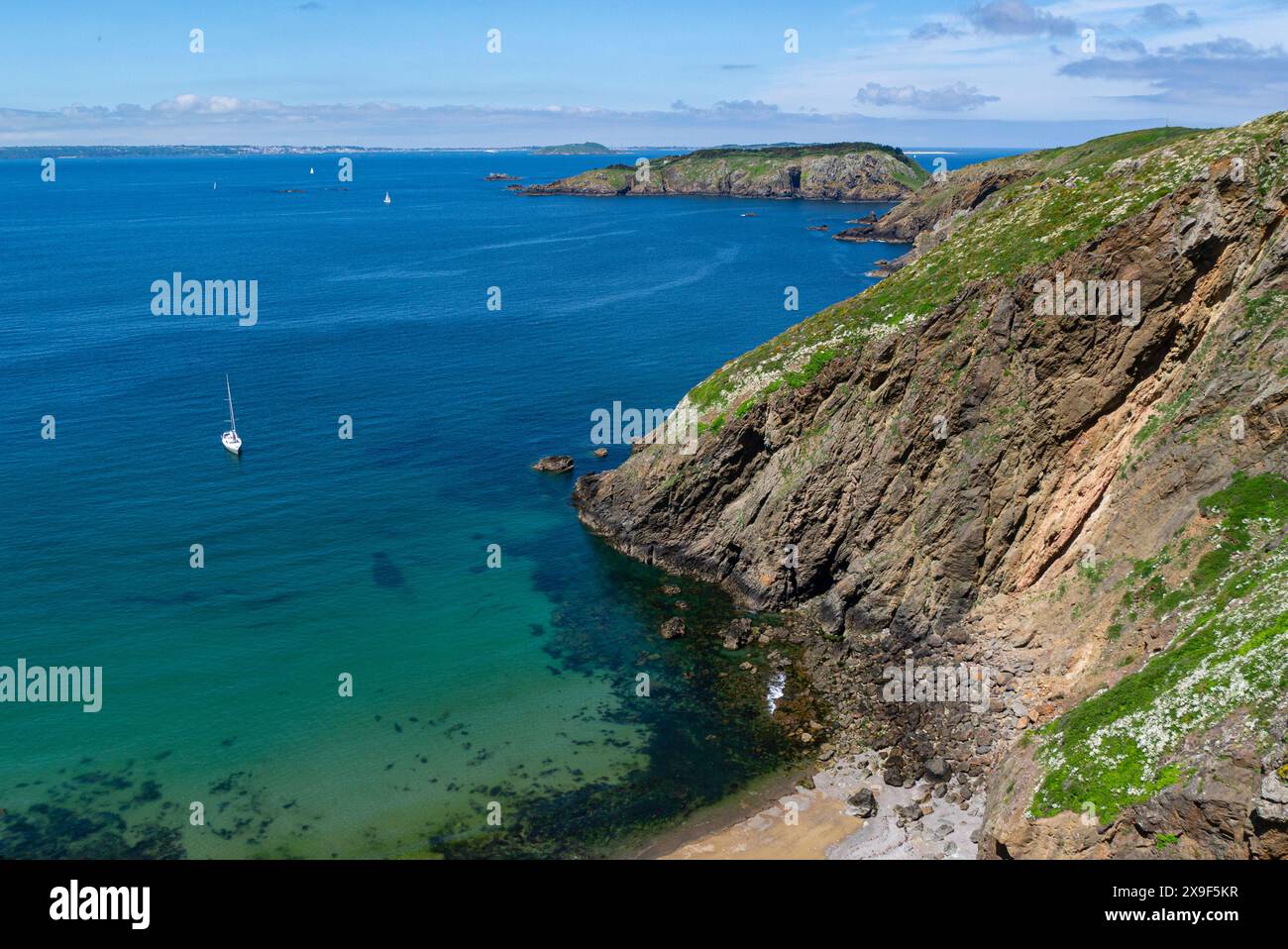 Affacciato sulla spiaggia di Grand Greve con yacht bianco ormeggiato dal ponte di la Coupee che collega Big alle isole del Canale di Little Sark in un incantevole giorno di maggio di sole Foto Stock