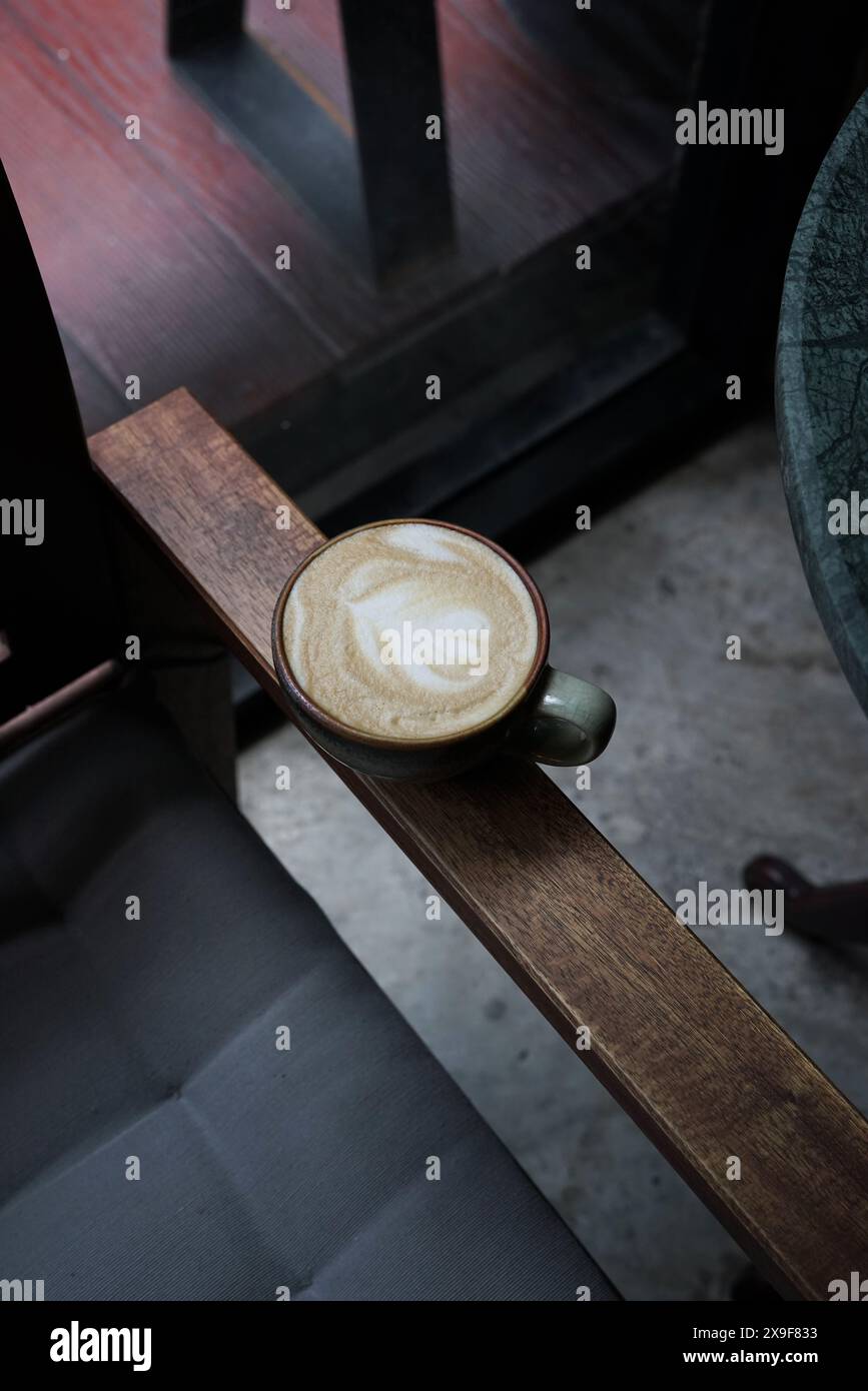 Bevanda a base di cuore di latte con vecchia tazza in ceramica sulla sedia in legno resistente agli agenti atmosferici, atmosfera vintage. Foto Stock