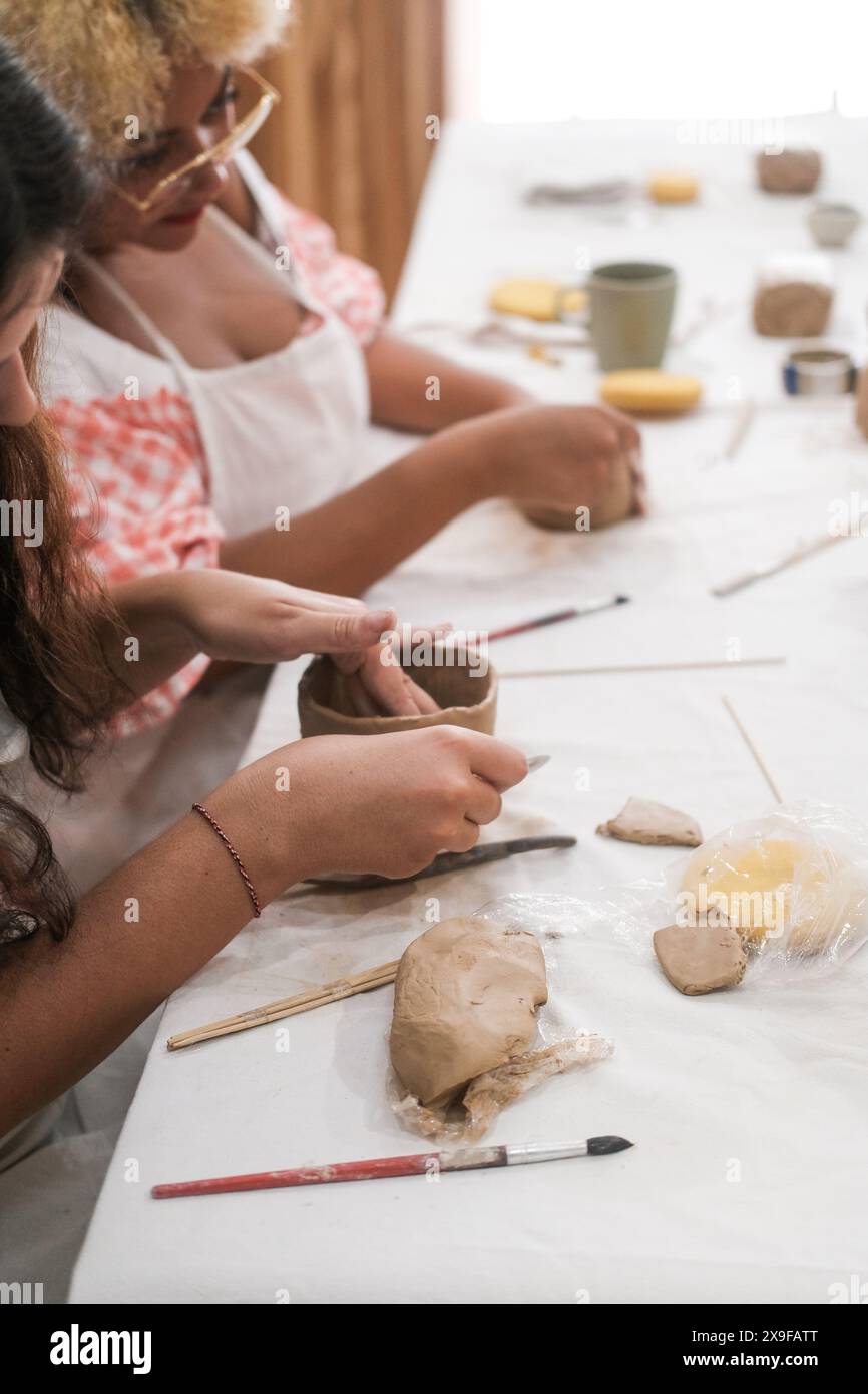 Ritratto verticale di due diverse donne sedute in un laboratorio di ceramica Foto Stock