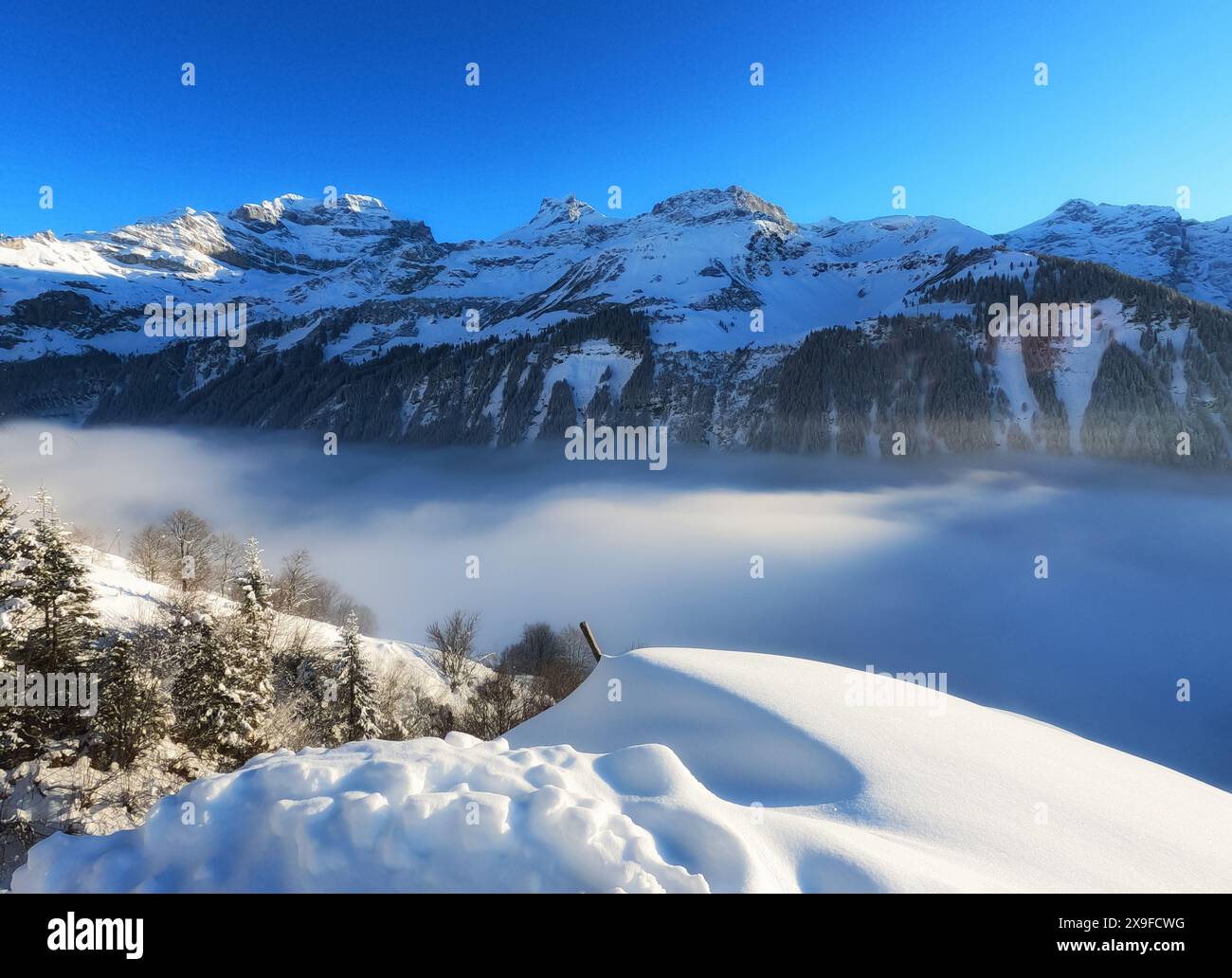 Vista aerea di nuvole basse su un paesaggio alpino innevato, passo di chiusa, Svizzera Foto Stock