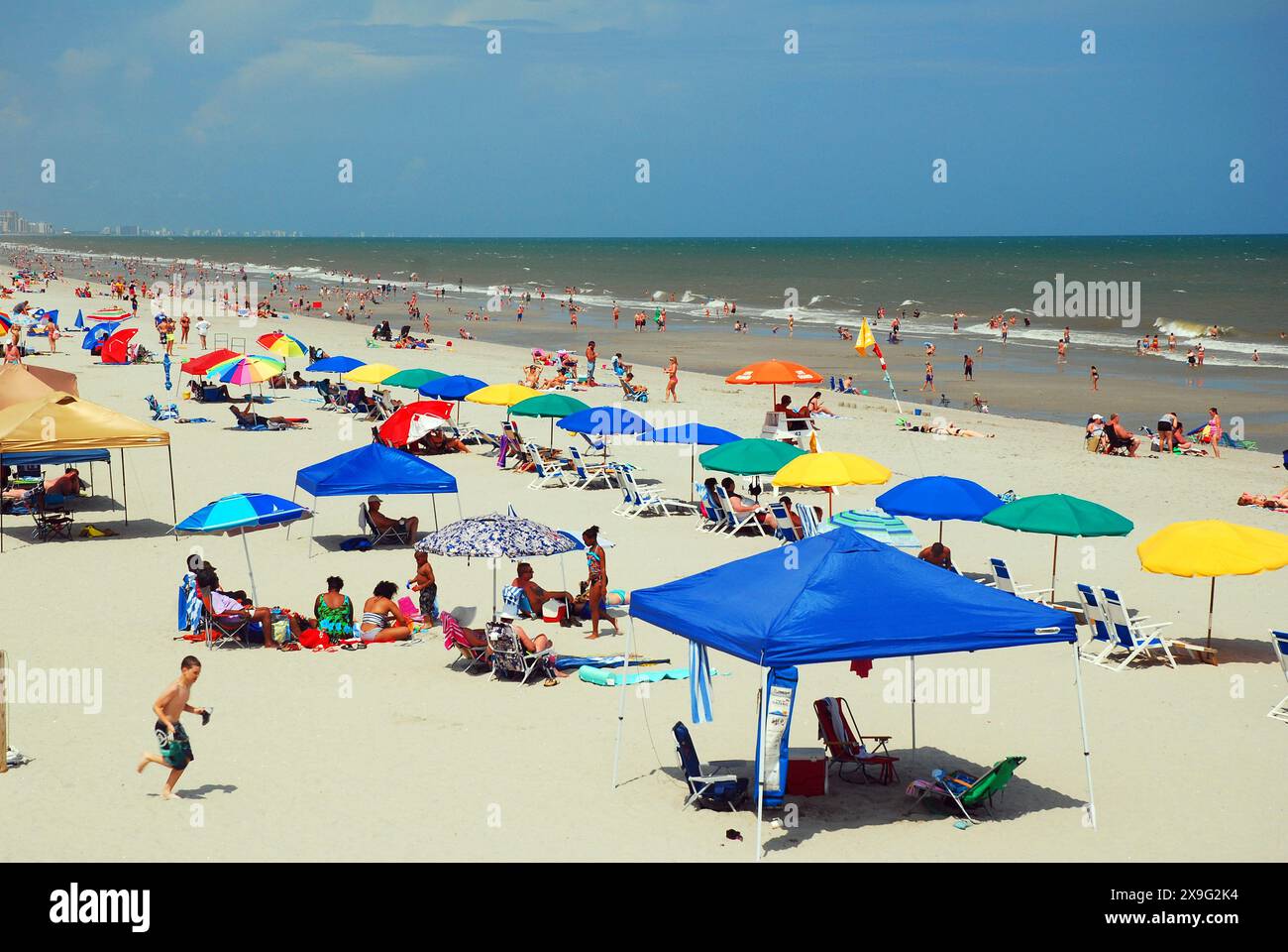 Gli amanti della spiaggia possono prendere la maggior parte della sabbia, seduti sotto gli ombrelloni lungo la riva di Myrtle Beach, South Carolina, in una giornata di vacanza estiva Foto Stock