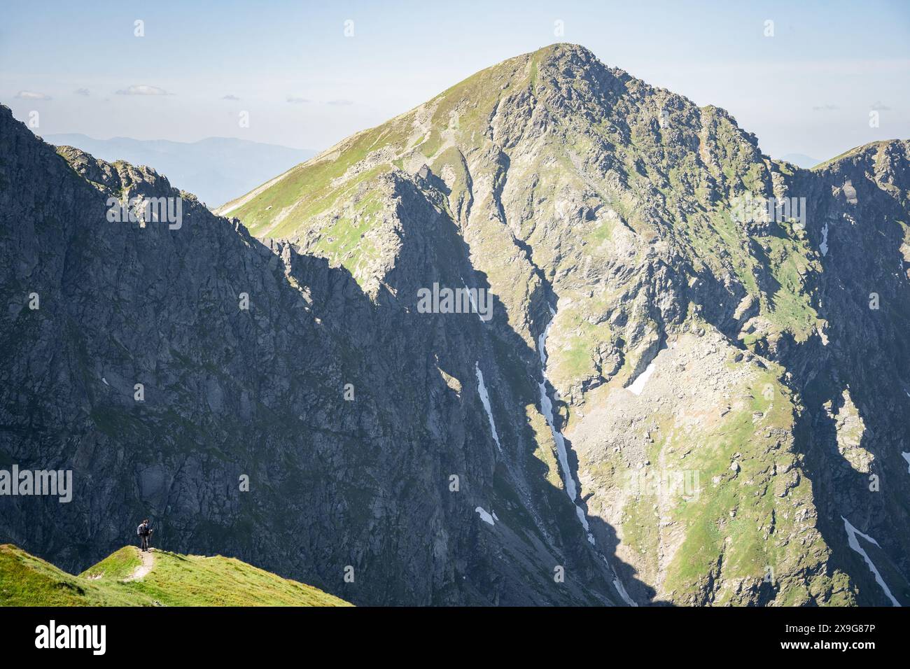 Piccoli escursionisti in lontananza che guardano indietro su massicce montagne rocciose alle loro spalle, Slovacchia, Europa Foto Stock