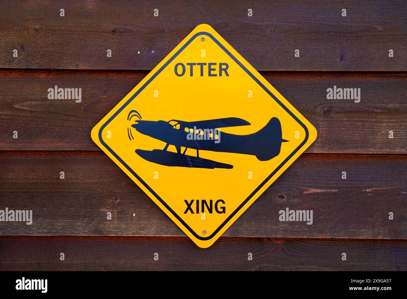 Segnaletica stradale umoristica a forma di diamante che segnala una "Otter xing" con il design di un idrovolante su sfondo giallo Foto Stock