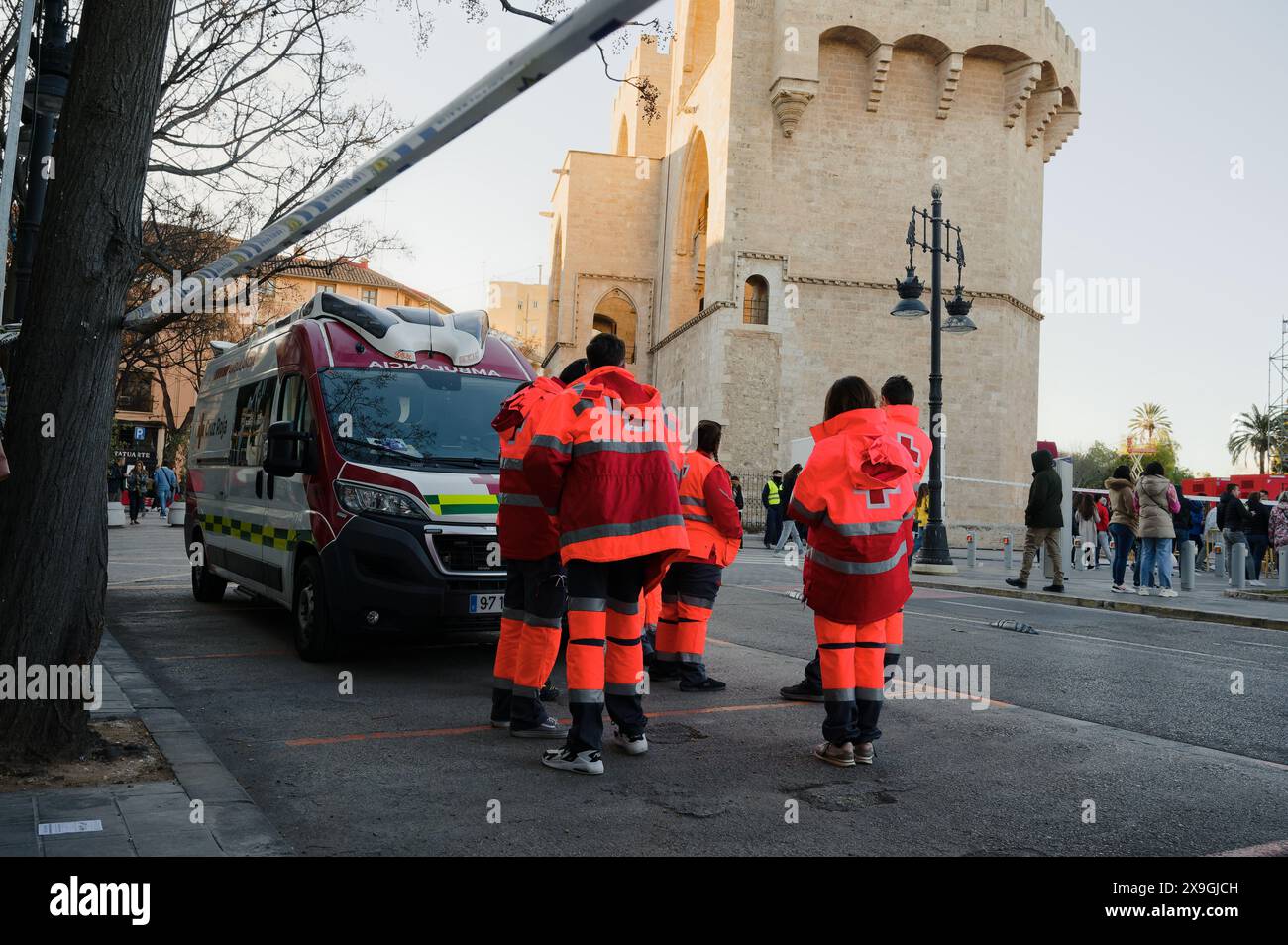I soccorritori in uniformi luminose si riuniscono vicino a una torre storica di valencia, preparandosi per i loro compiti durante le feste di las fallas Foto Stock