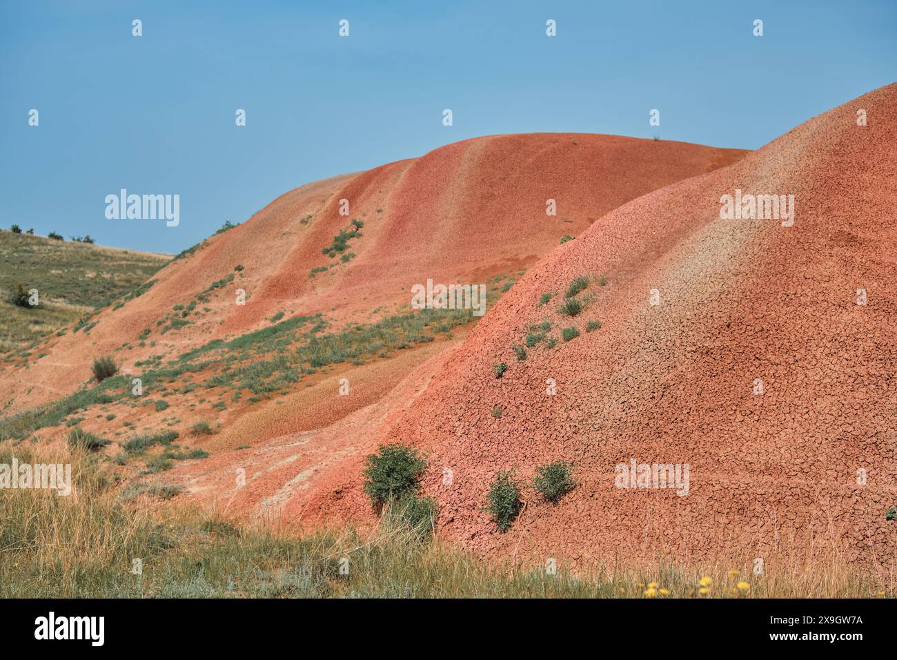 Vista panoramica delle colline rosse sotto il cielo blu luminoso. I colori vivaci creano un incredibile contrasto visivo, un invito a fare escursioni ed esplorare nuovi luoghi remoti Foto Stock