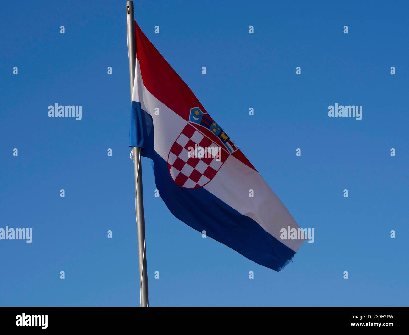 La bandiera croata sventolava nel vento contro un cielo azzurro, con le sue caratteristiche piazze rosse e bianche, la città vecchia di Dubrovnik con Foto Stock