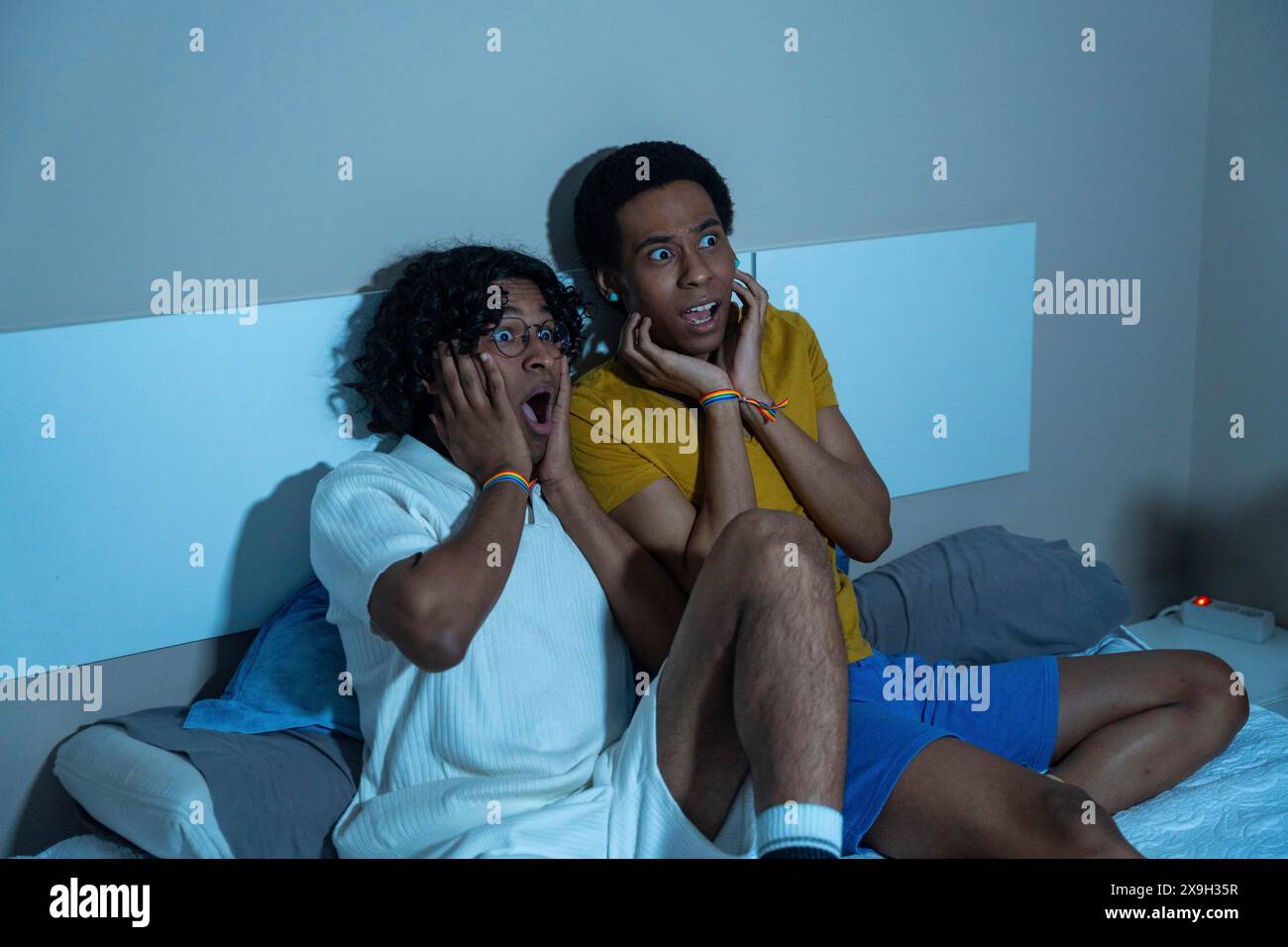 Coppia gay che guarda un film horror spaventoso di notte seduto a casa Foto Stock