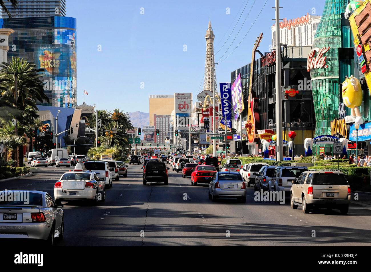 Las Vegas, Nevada, Stati Uniti, Nord America, Una strada trafficata con auto e una replica della Torre Eiffel e negozi su entrambi i lati, Las Vegas Strip Foto Stock