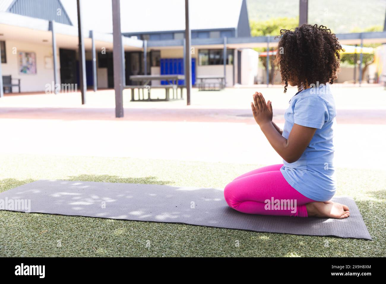 La ragazza birazziale pratica yoga a scuola, con spazio di copia Foto Stock